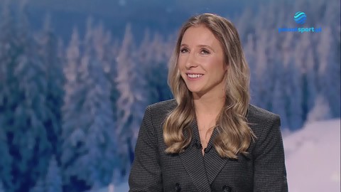 Luiza Złotkowska, kobieta z długimi blond włosami i w ciemnej marynarce, uśmiecha się. W tle widok na zimowy krajobraz z ośnieżonymi drzewami.