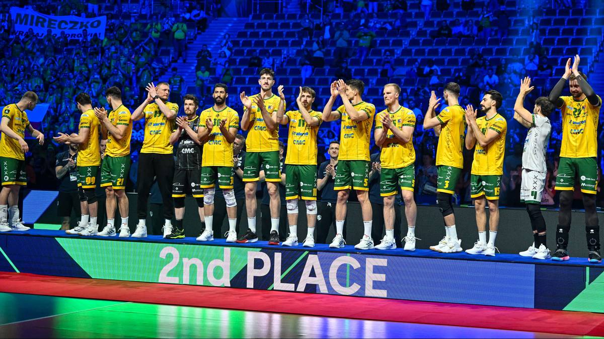 Drużyna siatkarzy w żółtych strojach stoi na podium, świętując drugie miejsce.