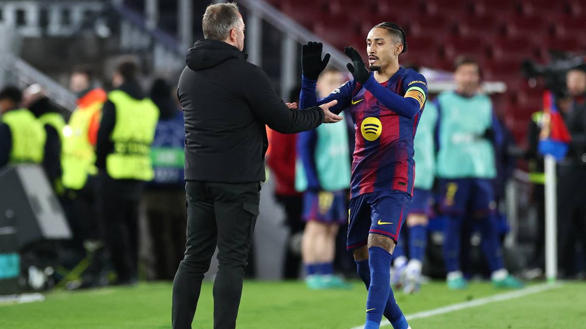 Piłkarz FC Barcelona Raphinha rozmawia z trenerem na boisku.