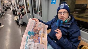 Mężczyzna w czapce zimowej i okularach siedzi w pociągu i trzyma gazetę z nagł&oacute;wkami "Fantastici" i "Corriere della Sera".