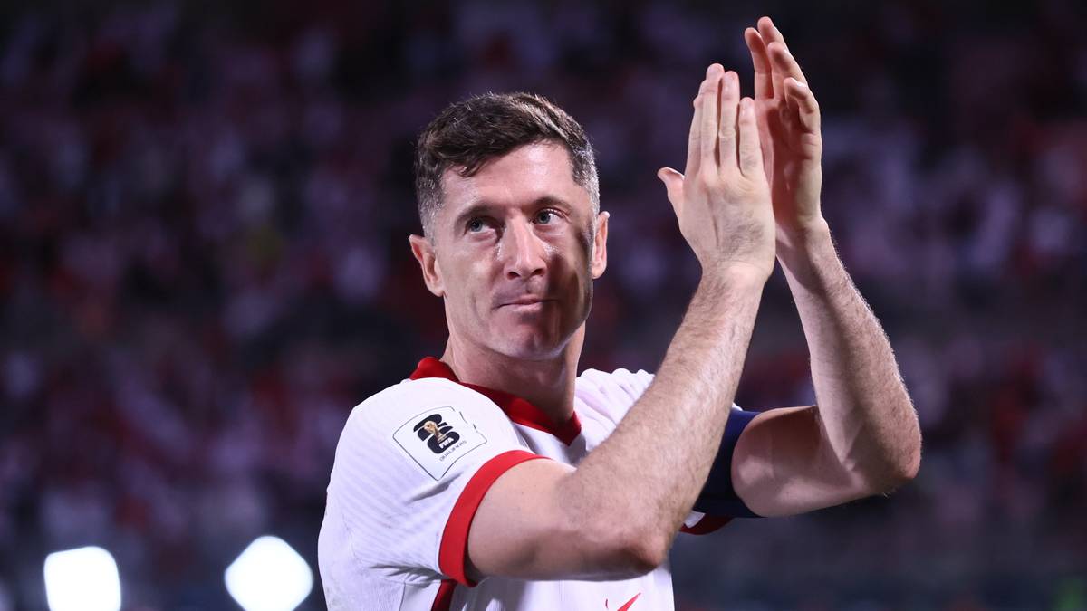 Robert Lewandowski, piłkarz reprezentacji Polski, klaszcze na tle trybun stadionu.