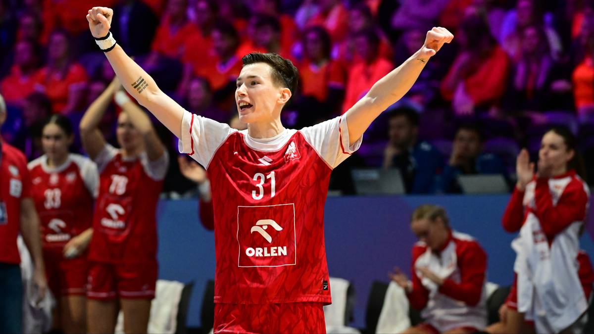 Piłkarz ręczny w czerwonej koszulce z numerem 31 unosi ręce w geście zwycięstwa.