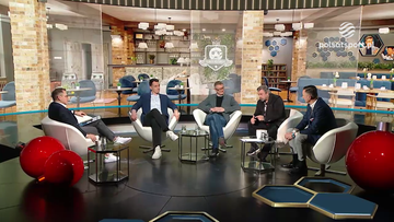 Czterech mężczyzn siedzi w fotelach podczas dyskusji w studiu telewizyjnym.