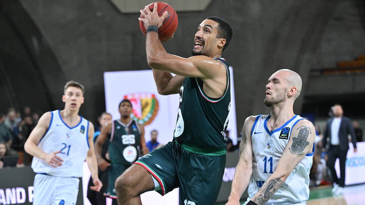 Gracz w zielonym stroju wyskakuje do rzutu koszykówką.