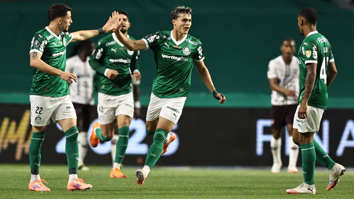 Piłkarze w zielonych koszulkach świętujący zwycięstwo na boisku piłkarskim.