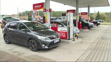 Kolejka samochod&oacute;w osobowych na stacji paliw przy dystrybutorach.