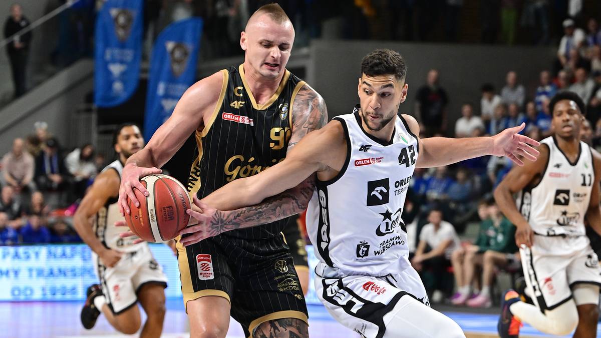 Dwóch zawodników drużyny koszykarskiej walczy o piłkę na boisku.