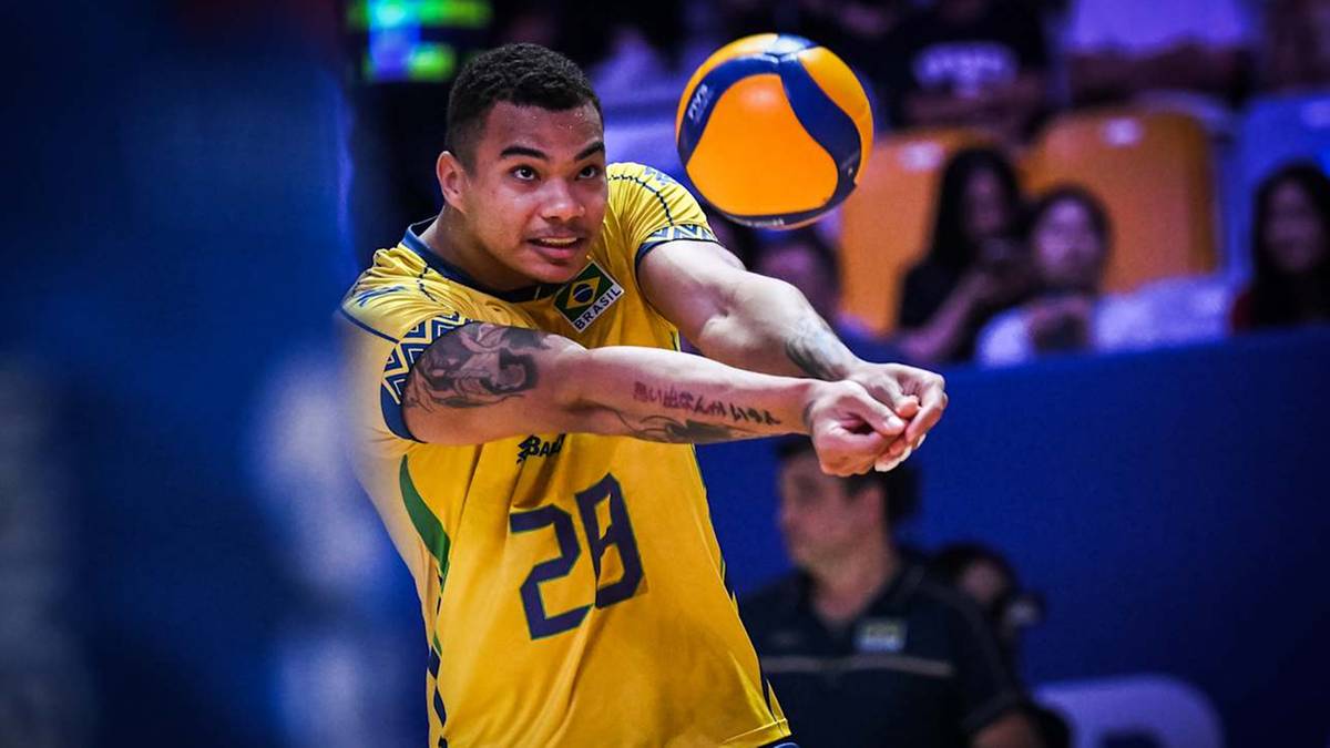 Siatkarz w żółtej koszulce z numerem 29 odbija piłkę do siatkówki.