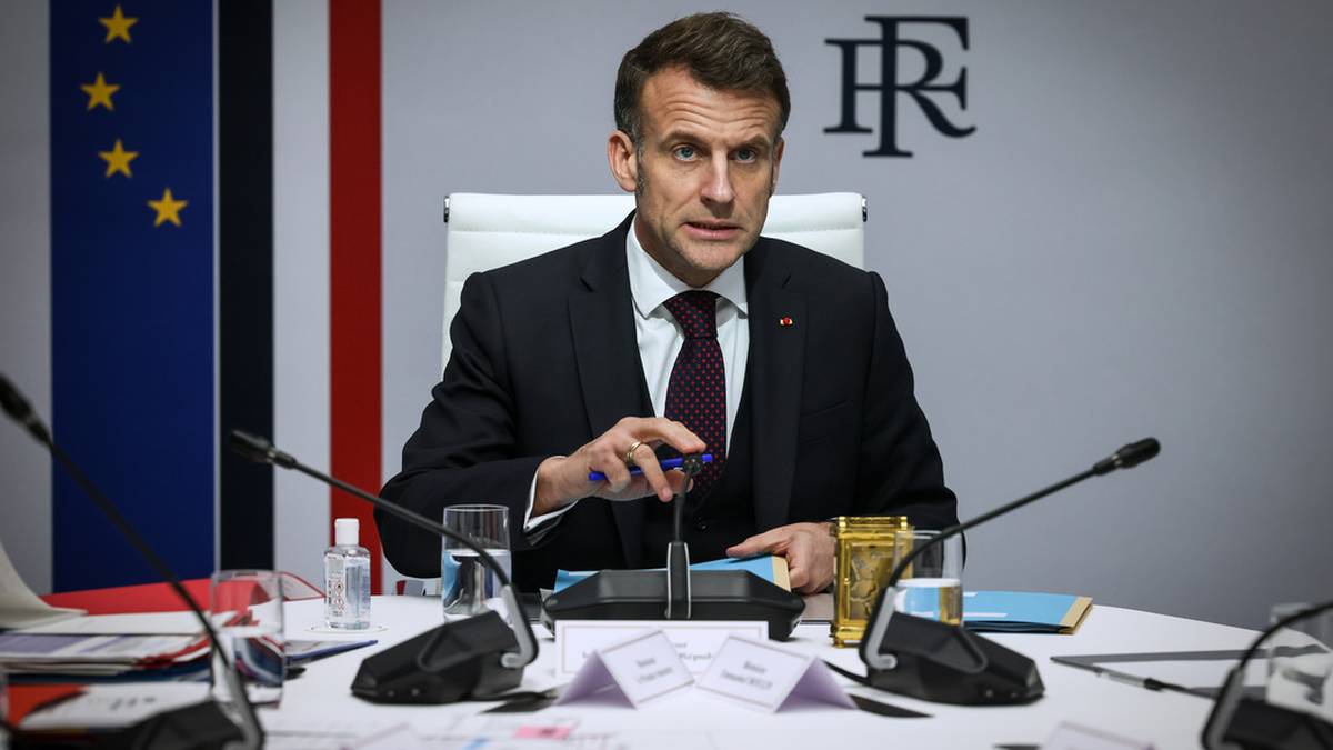 Prezydent Francji Emmanuel Macron siedzi przy stole podczas spotkania.