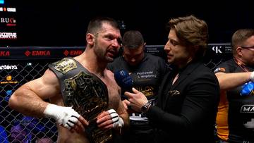 Szymon Kołecki w pasie mistrzowskim rozmawia z dziennikarzem po walce MMA.