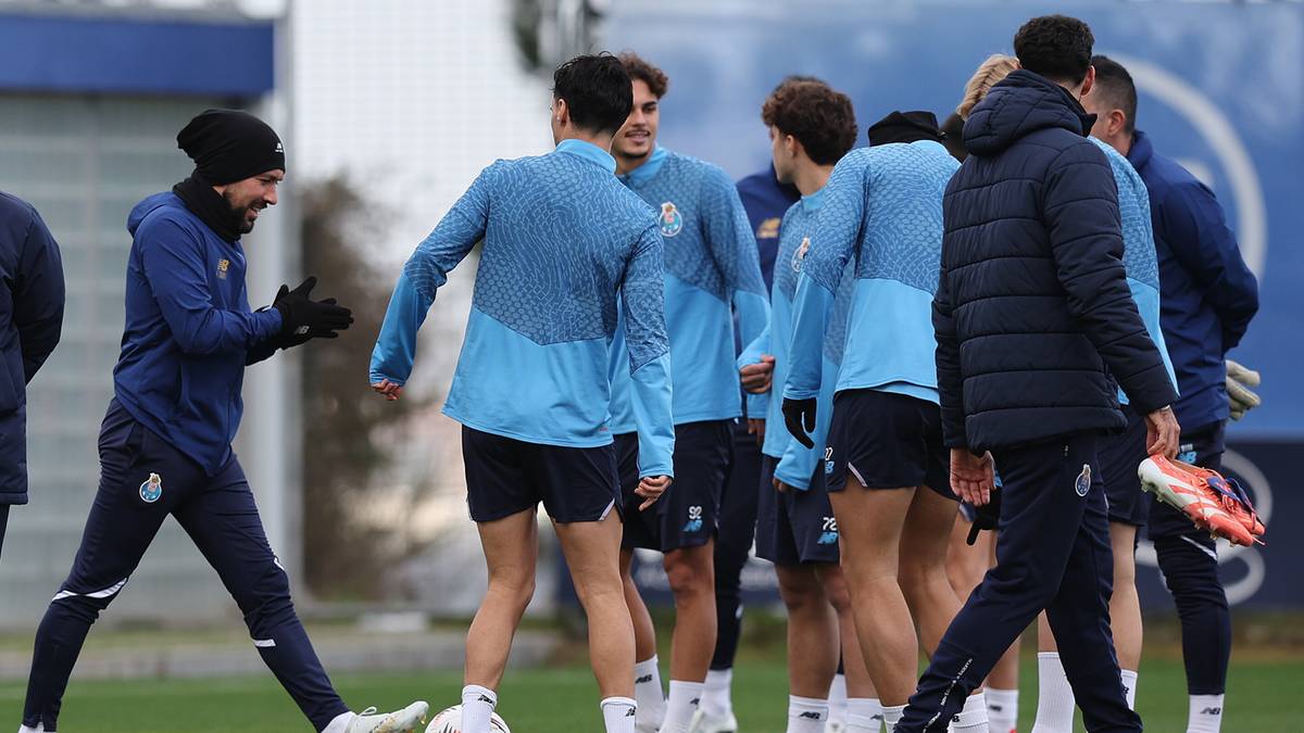 Piłkarze w niebieskich strojach treningowych rozmawiają na boisku piłkarskim.