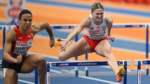 Dwie lekkoatletki biegnące przez płotki na bieżni.