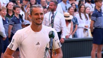 Alexander Zverev, tenisista, trzymający trofeum po zwycięstwie, uśmiecha się do tłumu.