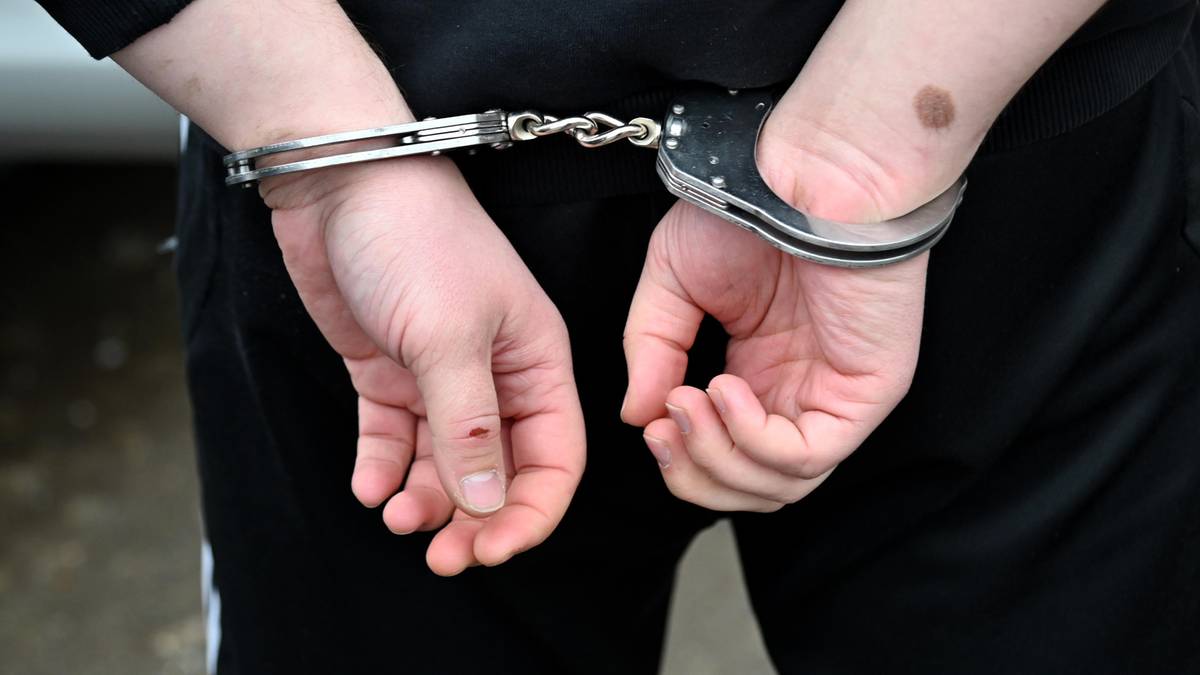 Ręce osoby zatrzymanej spięte kajdankami z tyłu.