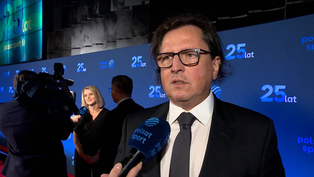 Paweł Wójcik w okularach i garniturze udziela wywiadu, trzymając w ręku mikrofon z logo Polsat Sport. W tle znajduje się niebieska ściana z napisem "25 lat Polsat Sport".