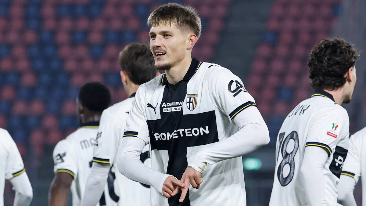 Piłkarz w białej koszulce z numerem 7 na plecach, rozmawiający z kolegą z drużyny na boisku.