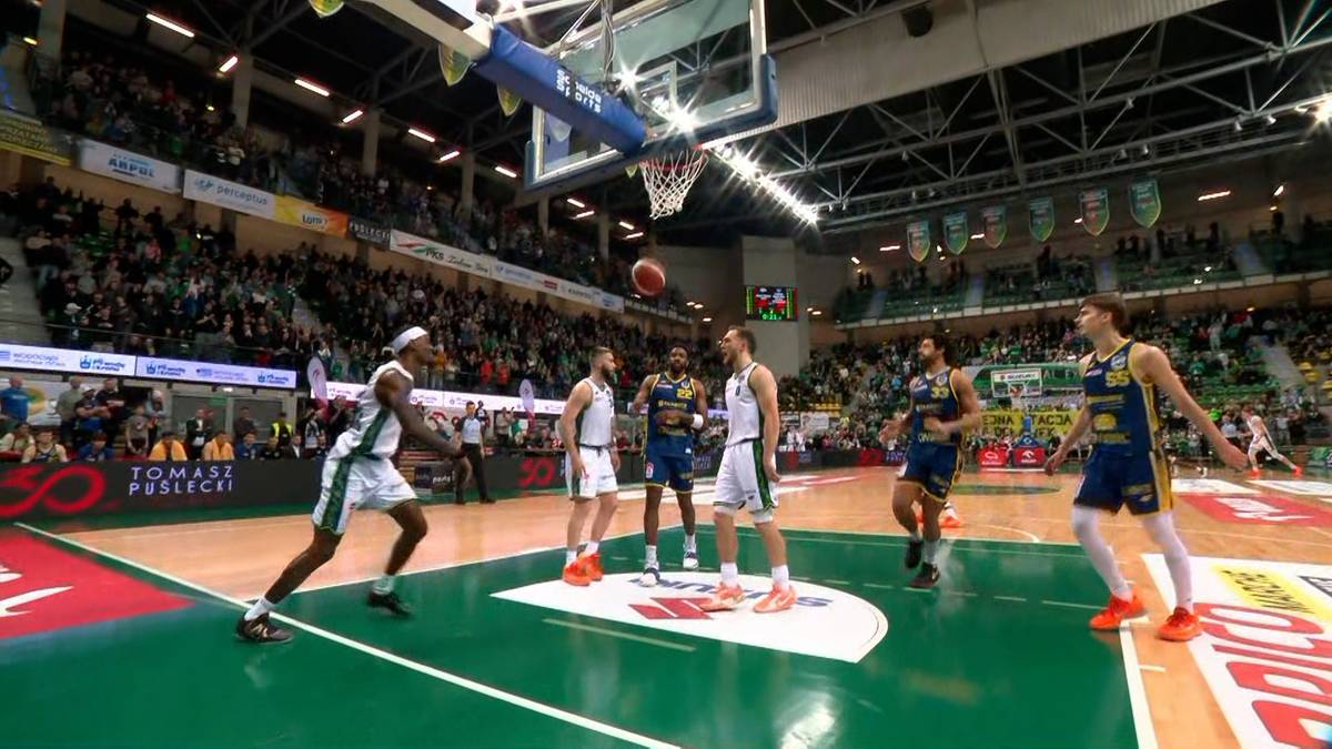 Pięciu koszykarzy na boisku podczas meczu, jeden z nich wykonuje rzut do kosza.