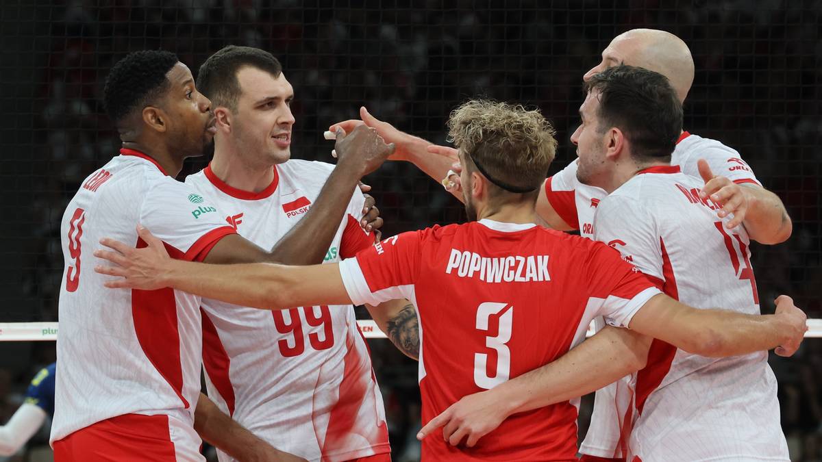 Grupa siatkarzy reprezentacji Polski w białych koszulkach świętuje zwycięstwo, przytulając się i unosząc ręce.