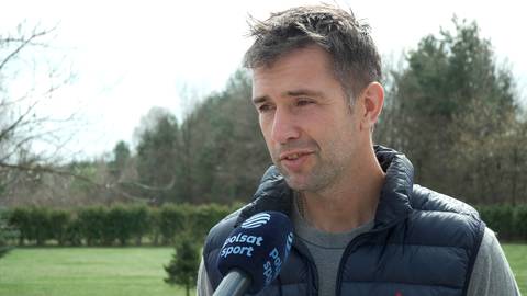 Portret mężczyzny udzielającego wywiadu, z mikrofonem Polsat Sport przed ustami.