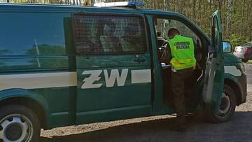 Funkcjonariusz Żandarmerii Wojskowej przy pojeździe służbowym.