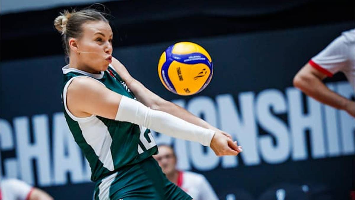 Sięgająca po piłkę siatkarka w zielono-białym stroju sportowym, z białymi ochraniaczami na przedramionach. Na tle ciemnej ściany z napisem "CHAMPIONSHIP".