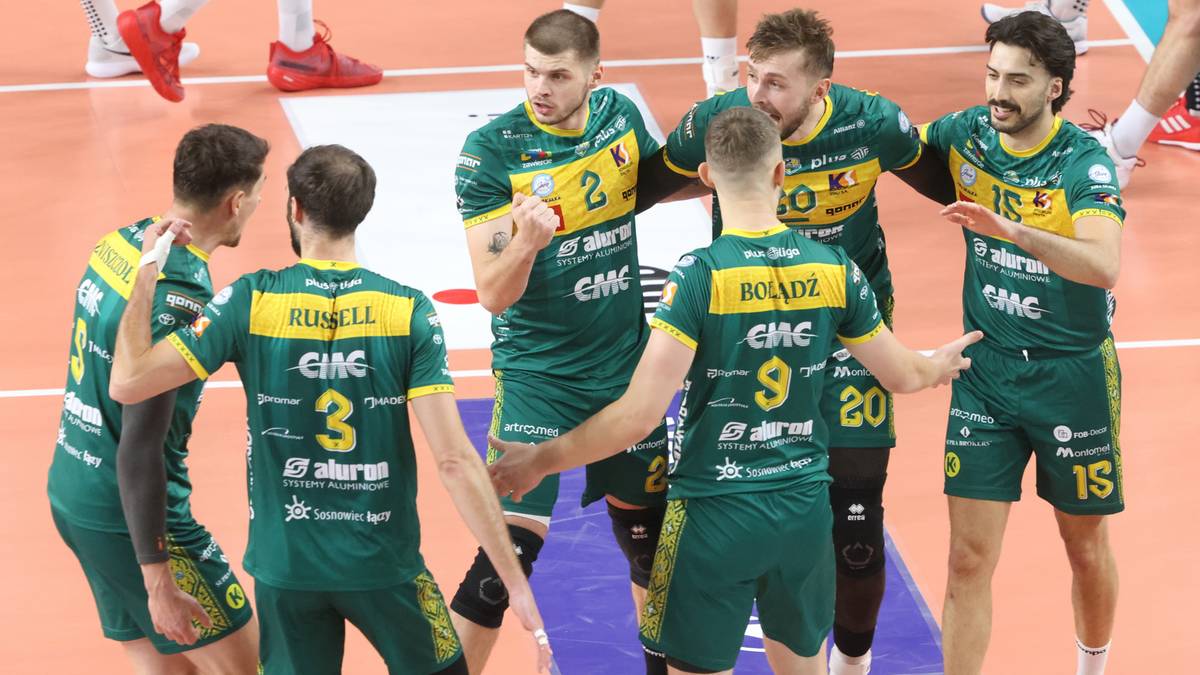 Drużyna siatkarzy w zielonych strojach świętuje na boisku.