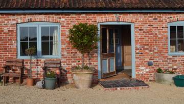 Ceglany dom z niebieskimi okiennicami i drzwiami.