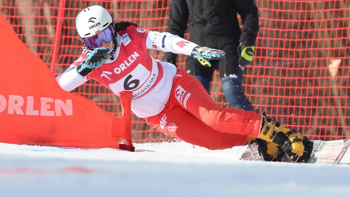 Zawodniczka snowboardu w czerwono-białym stroju podczas zjazdu na śniegu.