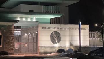 Budynek ambasady Stan&oacute;w Zjednoczonych Ameryki w Oslo nocą, oświetlony z widocznym logo ambasady.