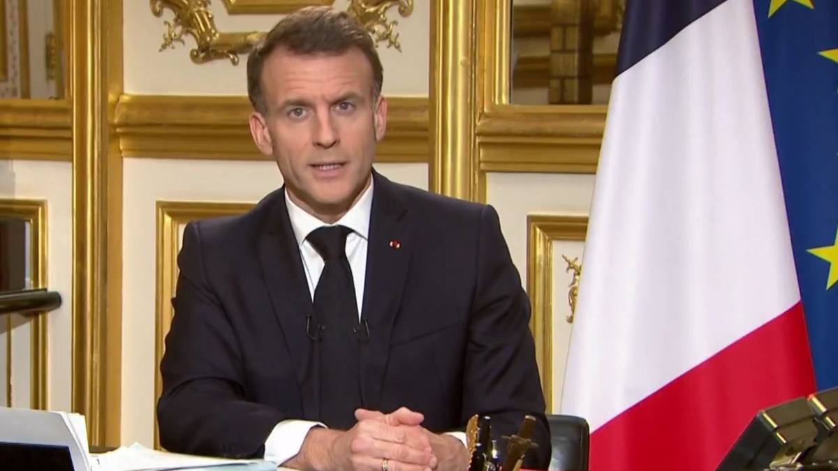 Prezydent Francji Emmanuel Macron przemawia przy biurku, obok flagi Francji i Unii Europejskiej.