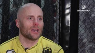 Mężczyzna z łysą głową i zarostem, ubrany w żółto-czarną koszulkę sportową.