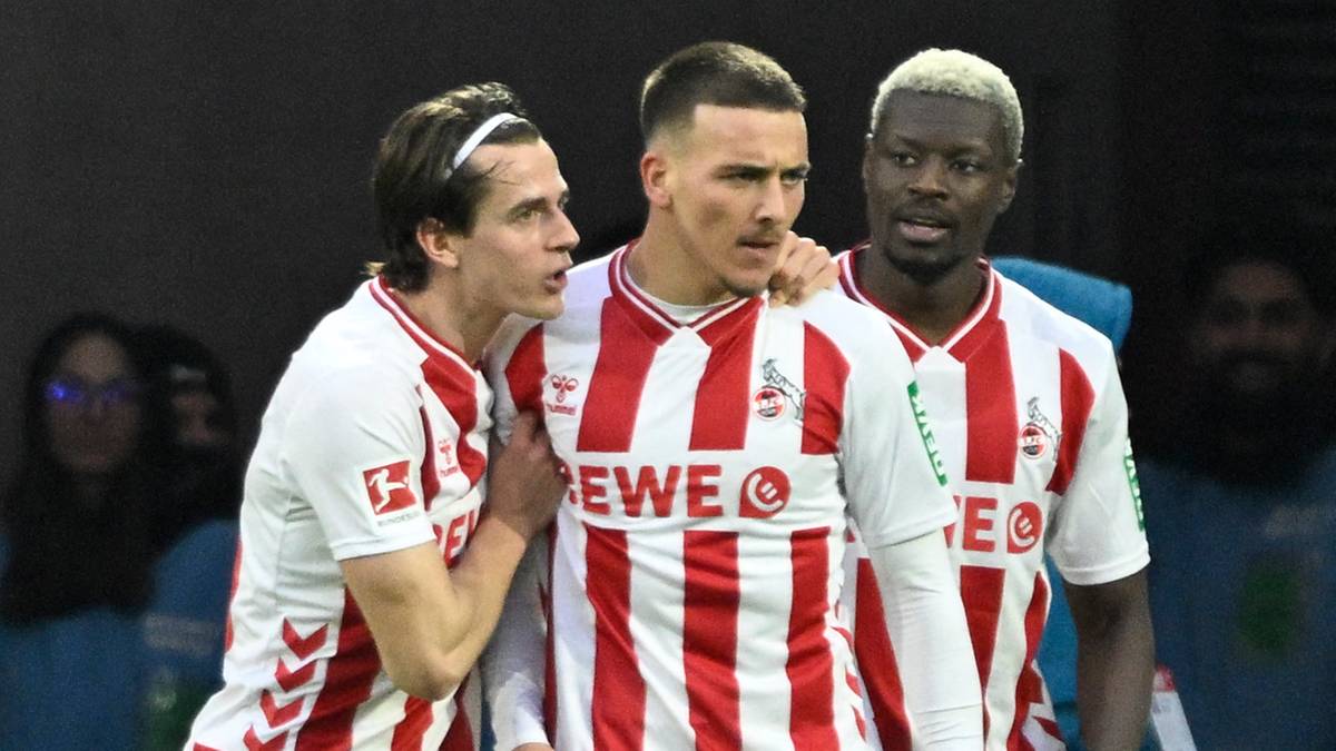 Trzech piłkarzy FC Koeln w czerwono-białych pasiaste strojach świętuje gola na boisku.