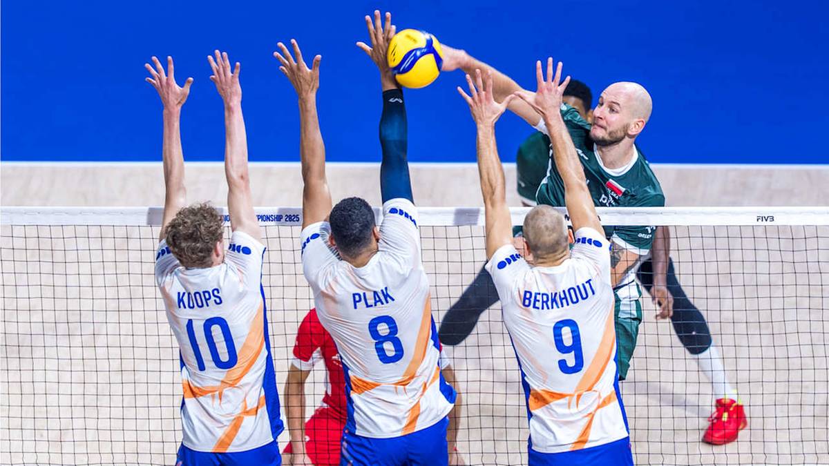 Siatkarze w akcji podczas meczu siatkówki na Mistrzostwach Świata. Trzech zawodników w białych koszulkach z numerami 10, 8 i 9 próbuje zablokować atak przeciwnika, który znajduje się po drugiej stronie siatki. Wszyscy zawodnicy mają uniesione ręce do góry, a jeden z nich próbuje uderzyć piłkę do odbicia.