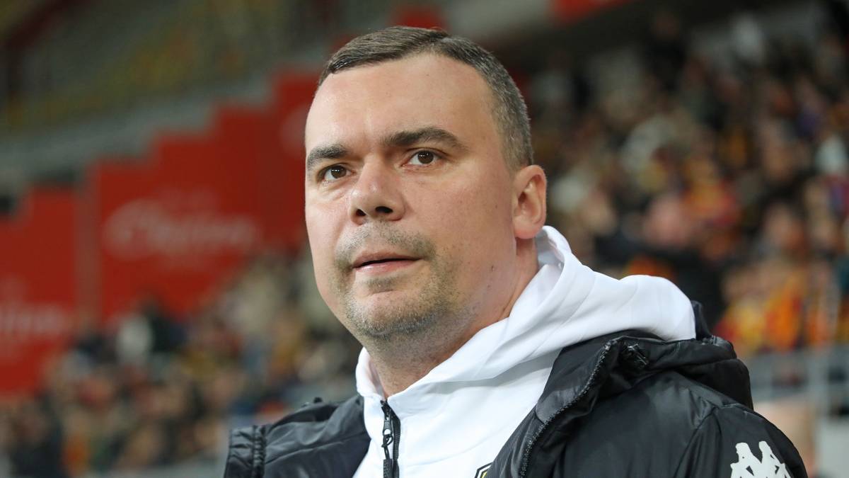 Trener piłkarski w kurtce sportowej z kapturem.