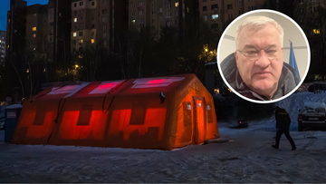 Pomarańczowy namiot podświetlony od środka na czerwono, stojący na śniegu, z budynkami mieszkalnymi w tle. Obok mężczyzna w ciemnym ubraniu.