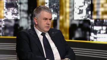 Mężczyzna w garniturze siedzi w studiu telewizyjnym.