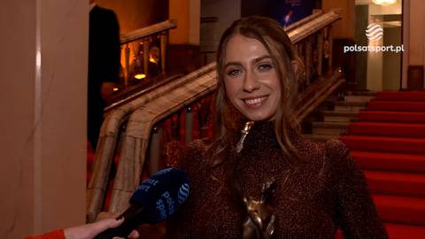 Klaudia Zwolińska uśmiecha się i trzyma mikrofon podczas wywiadu na czerwonym dywanie.
