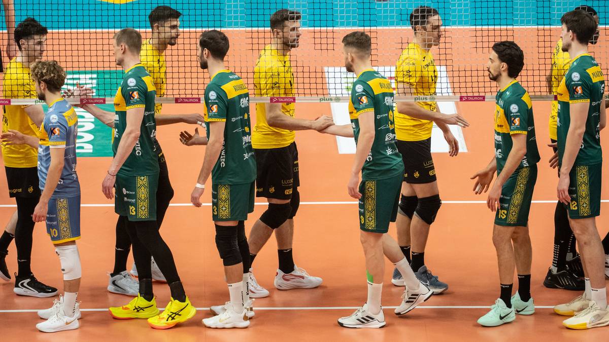 Siatkarze Aluronu CMC Warta Zawiercie w ż&oacute;łto-zielonych strojach stoją obok siebie na boisku siatkarskim, rozmawiają ze sobą i patrzą w r&oacute;żnych kierunkach.