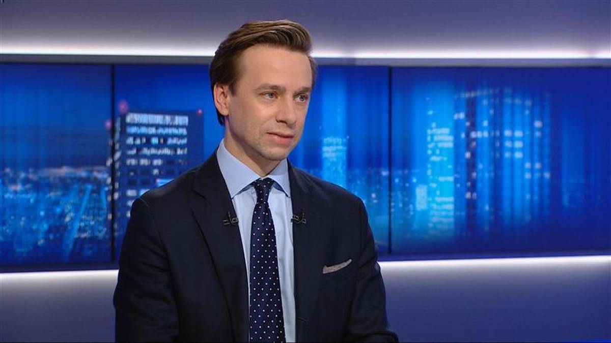 Mężczyzna w granatowym garniturze i z krawatem patrzy w bok.