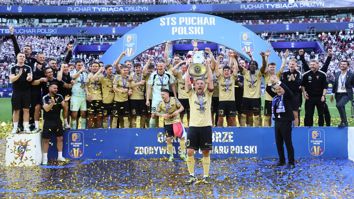 Drużyna piłkarska G&oacute;rnik Zabrze świętuje zdobycie Pucharu Polski, wznosząc trofeum na tle trybun stadionu.
