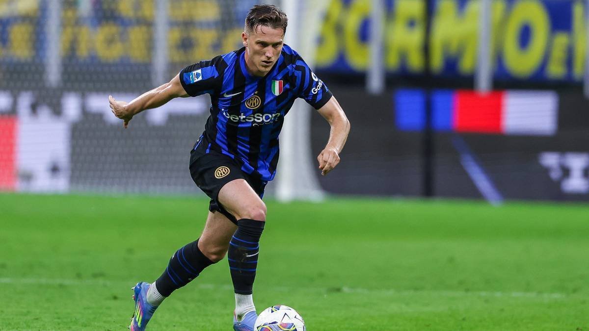 Piłkarz Piotr Zieliński w niebiesko-czarnej koszulce Inter Mediolan prowadzi piłkę na boisku.