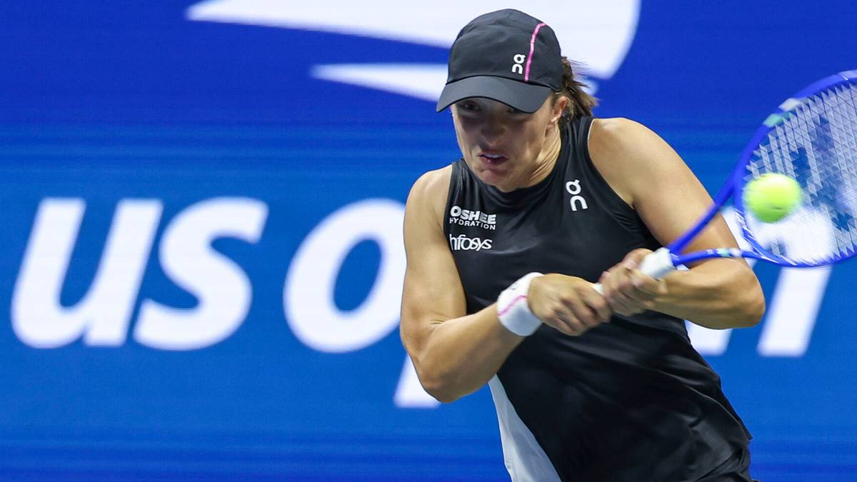 Iga Świątek podczas meczu tenisowego, odbijająca piłkę rakietą.