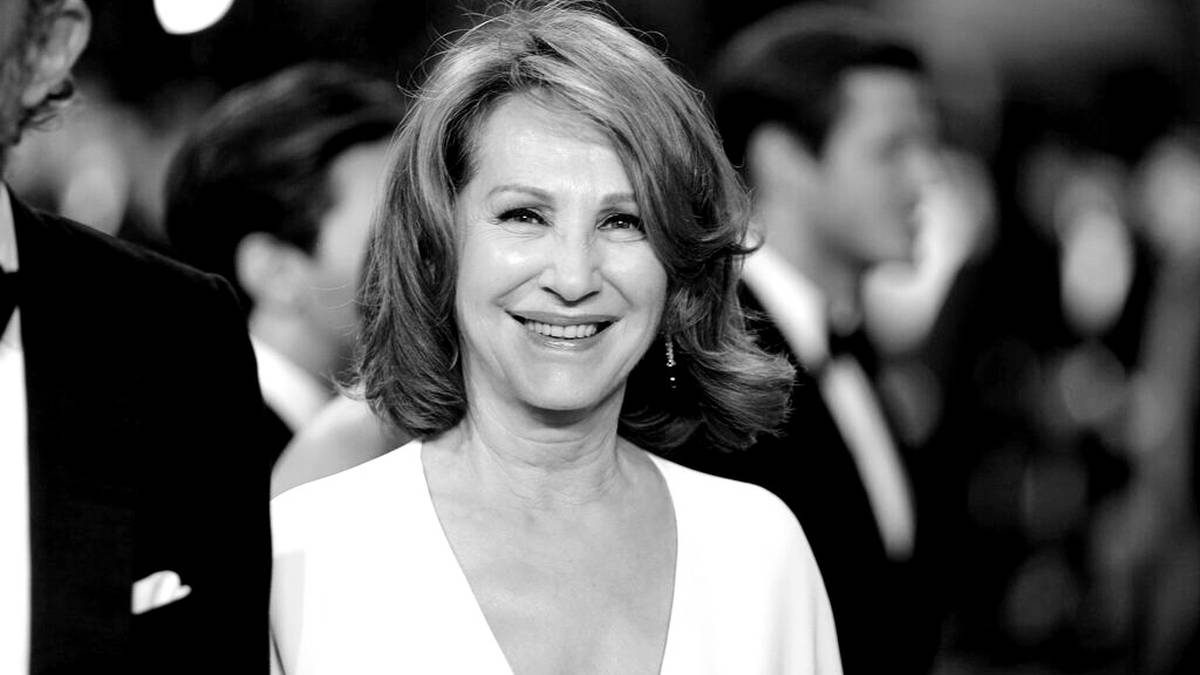 Portret Nathalie Baye, francuskiej aktorki, uśmiechniętej na tle innych os&oacute;b.