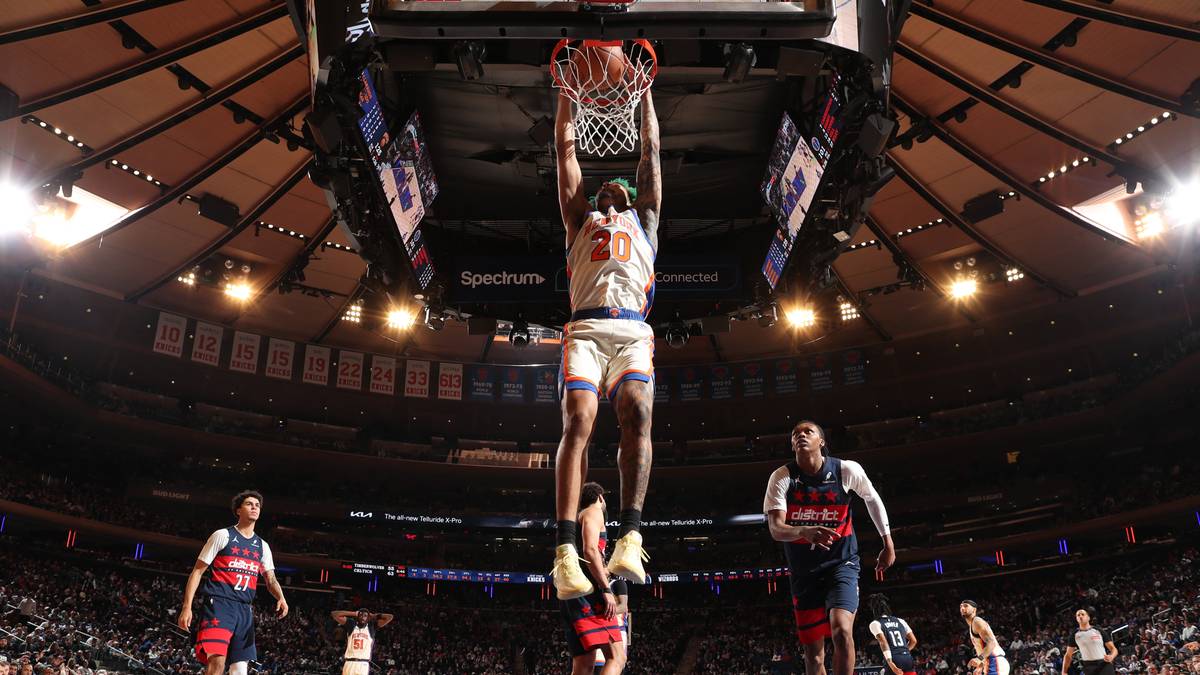 Gracz NBA wykonuje wsad do kosza podczas meczu, otoczony innymi zawodnikami na boisku.