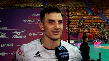 Portret Wassima Ben Tary, siatkarza, na tle hali sportowej z tablicami informacyjnymi i widownią.