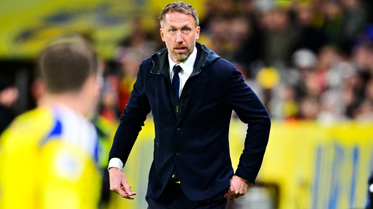 Trener Graham Potter w garniturze, z piłką w tle.