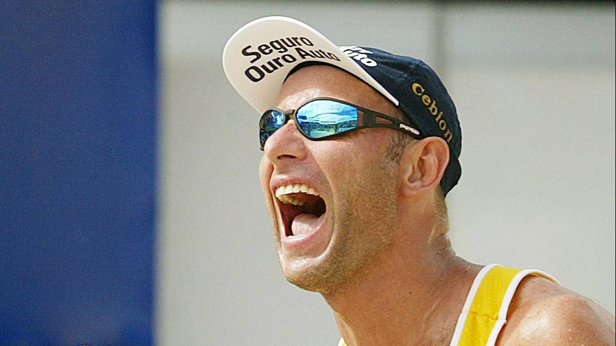 Zbliżenie na siatkarza plażowego w okularach przeciwsłonecznych i czapce z daszkiem, który krzyczy z otwartymi ustami.