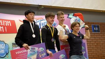 Czterech młodych ludzi stoi na podium, trzymając nagrody i medale.