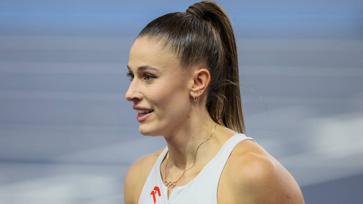 Kobieta lekkoatletka z włosami upiętymi w kucyk, w białej koszulce sportowej z widocznym logo.