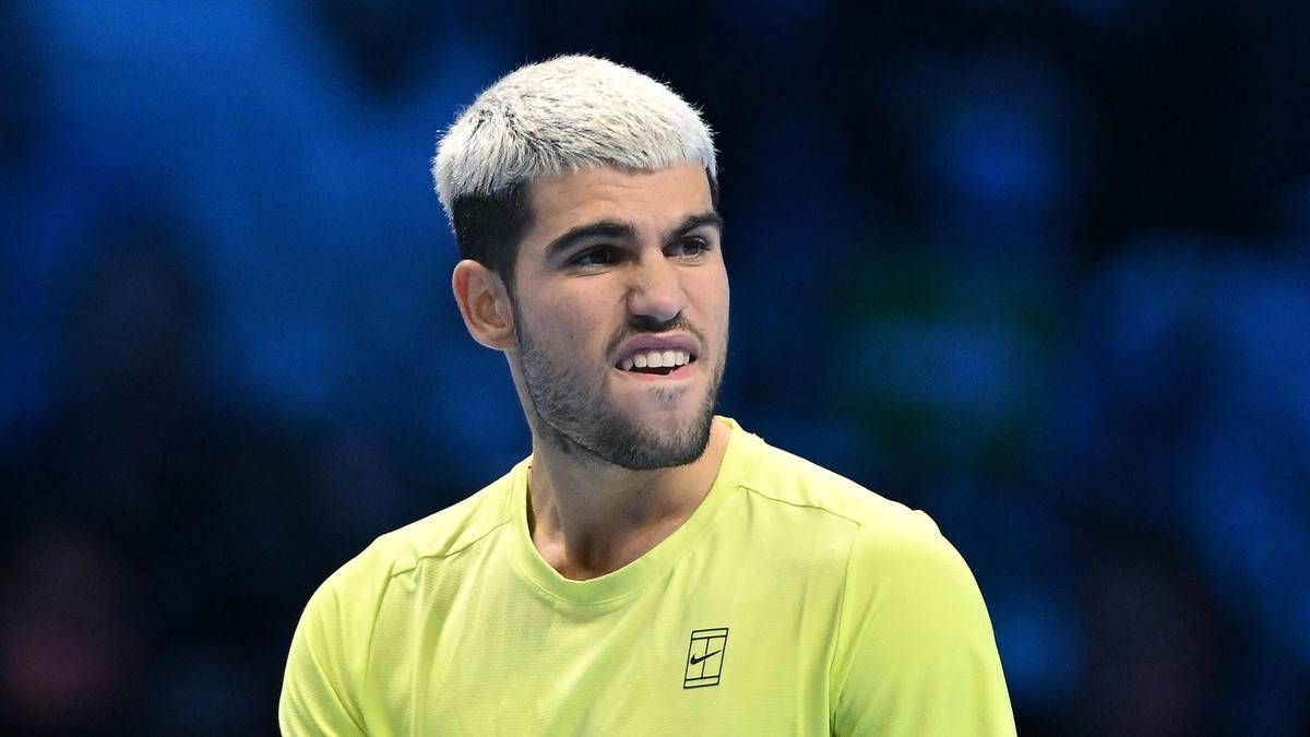 Carlos Alcaraz, młody tenisista z blond włosami, ubrany w żółtą koszulkę, zamyślony podczas meczu.